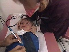 health care worker marking tube with a pen; child is on the papoose board with an adult soothing the child.