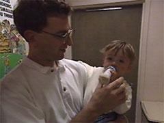 Father feeds child with bottle.